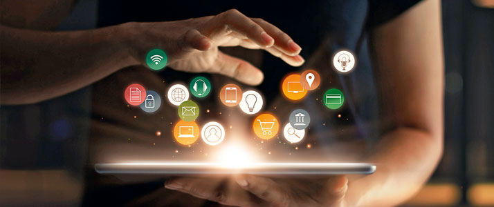 Über einem leuchtenden Tablet schweben verschiedene digitale Symbole. Ein Person hält das Tablet mit einer Hand vor sich, eine andere Hand schwebt über dem Tablet.