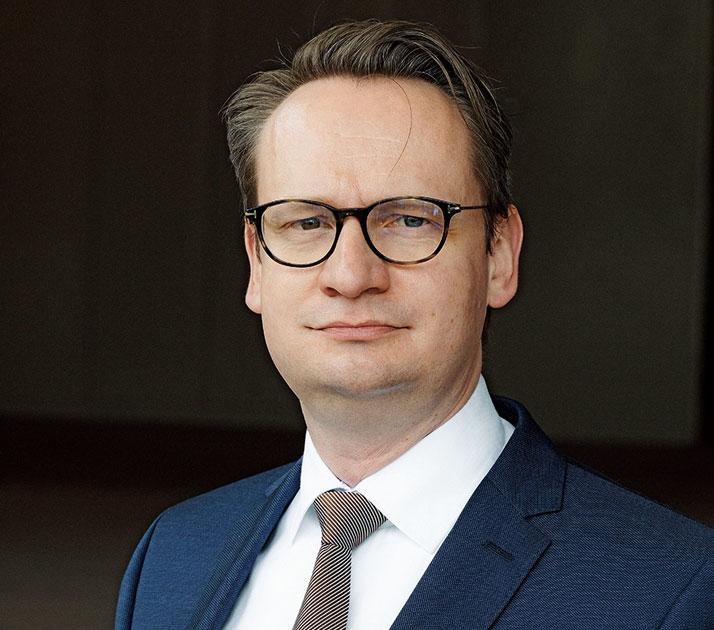Ein Portrait von Dr. Michael Rauterkus, Leiter der Dezernate Wirtschaft und Digitalisierung der Stadtverwaltung Düsseldorf. Er trägt eine Brille und einen Anzug und lächelt leicht in die Kamera.