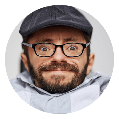 Portrait des Autoren und Aktivisten Raul Krauthausen. Er trägt eine graue Kappe und eine schwarzgerahmte Brille.