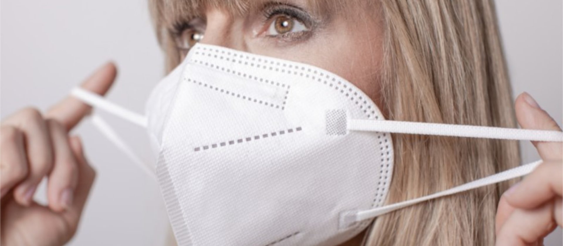 Eine blonde Frau verwendet eine FFP2-Maske, um sich gegen eine Corona-Infektion zu schützen.